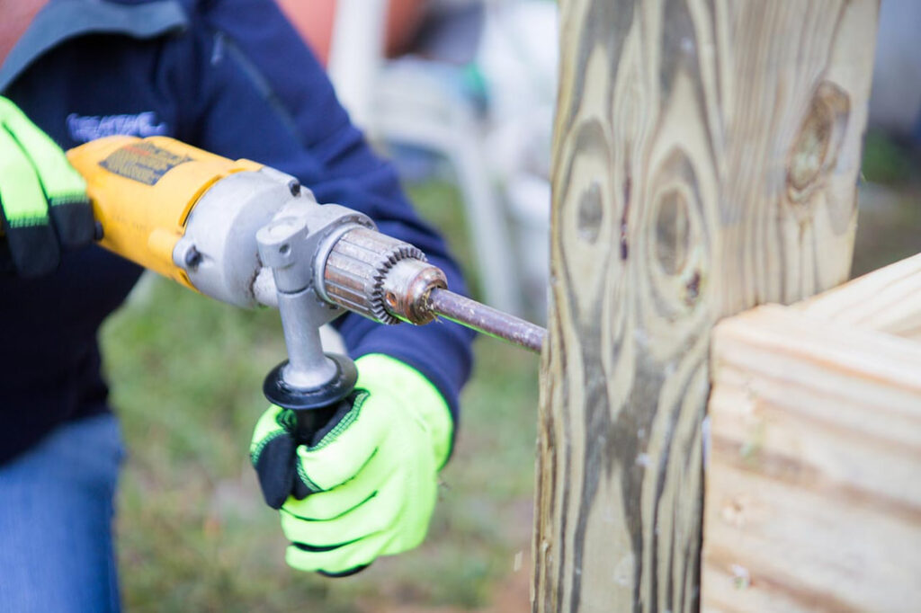 person using a hammer drill into a post