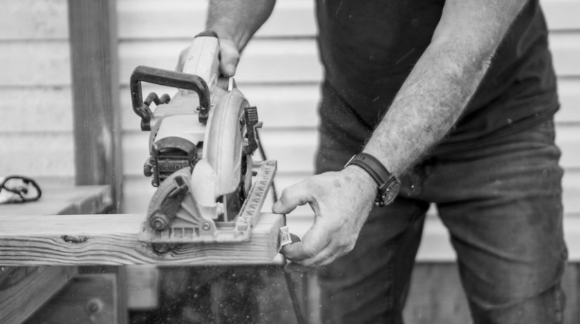 man using a skillsaw to cut lumber